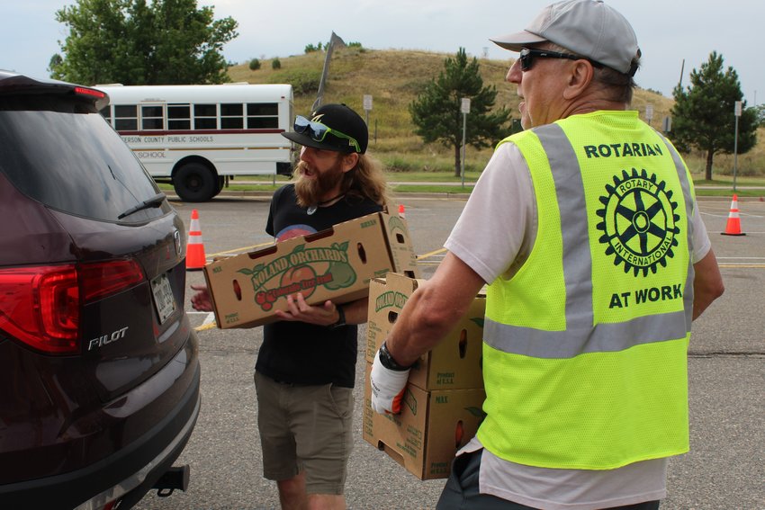 Volunteers for the Rotary Club of Golden load peaches into a customer's car during the "Peaches for a Purpose" pickup Aug. 20 at Golden High School. The Rotary Club sold about 1,700 boxes of peaches, raising about $30,000.